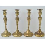 Four matching heavy turned brass candlesticks each measuring 23cm high.