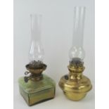 Two Victorian oil lamps. One with brass reservoir the other glass. Both with chimneys.