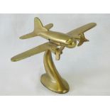 An Art Deco style brass desk piece in the form of a twin-propeller airplane on swept stand.