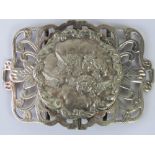 A large white metal belt buckle, central circular plaque with repoussé depiction of cherubs,