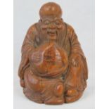 A carved bamboo figure of Shou-xing, seated and holding a large cumquat; 15cm high.