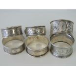 Six HM silver napkin rings; one pair and one with applied enameled shield, total weight 2.3ozt.
