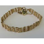 A 9ct gold four bar bracelet, hallmarked 375, complete with heart padlock clasp and guard chain,