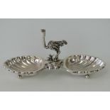 An unusual silver double salt surmounted by an ostrich figurine, shell shaped bowls with ball feet,