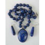 A lapis lazuli bead necklace with large oval pendant and earrings to match.
