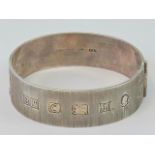 A heavy HM silver bangle with bark effect finish and engraved floral pattern,