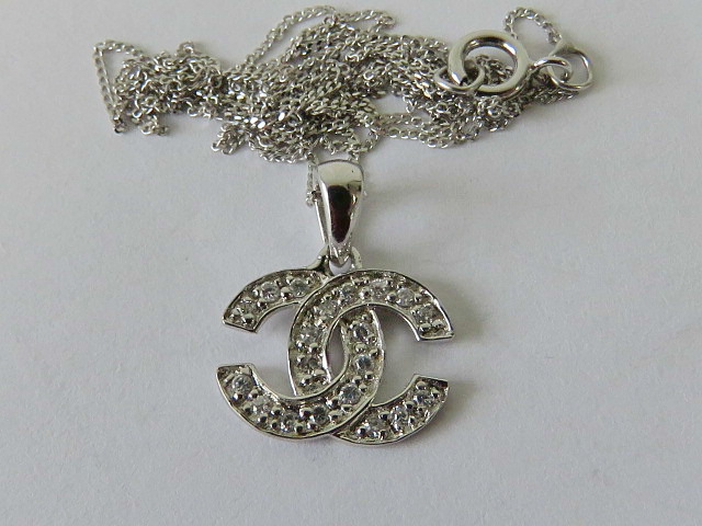 A 10ct white gold Chanel style interlocking C pendant, set with white stones,
