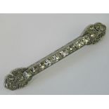 A platinum brooch set with white stones, central bar with channel set square cut stones,