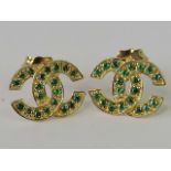 A pair of 10ct gold Chanel style interlocking C earrings, set with emeralds,