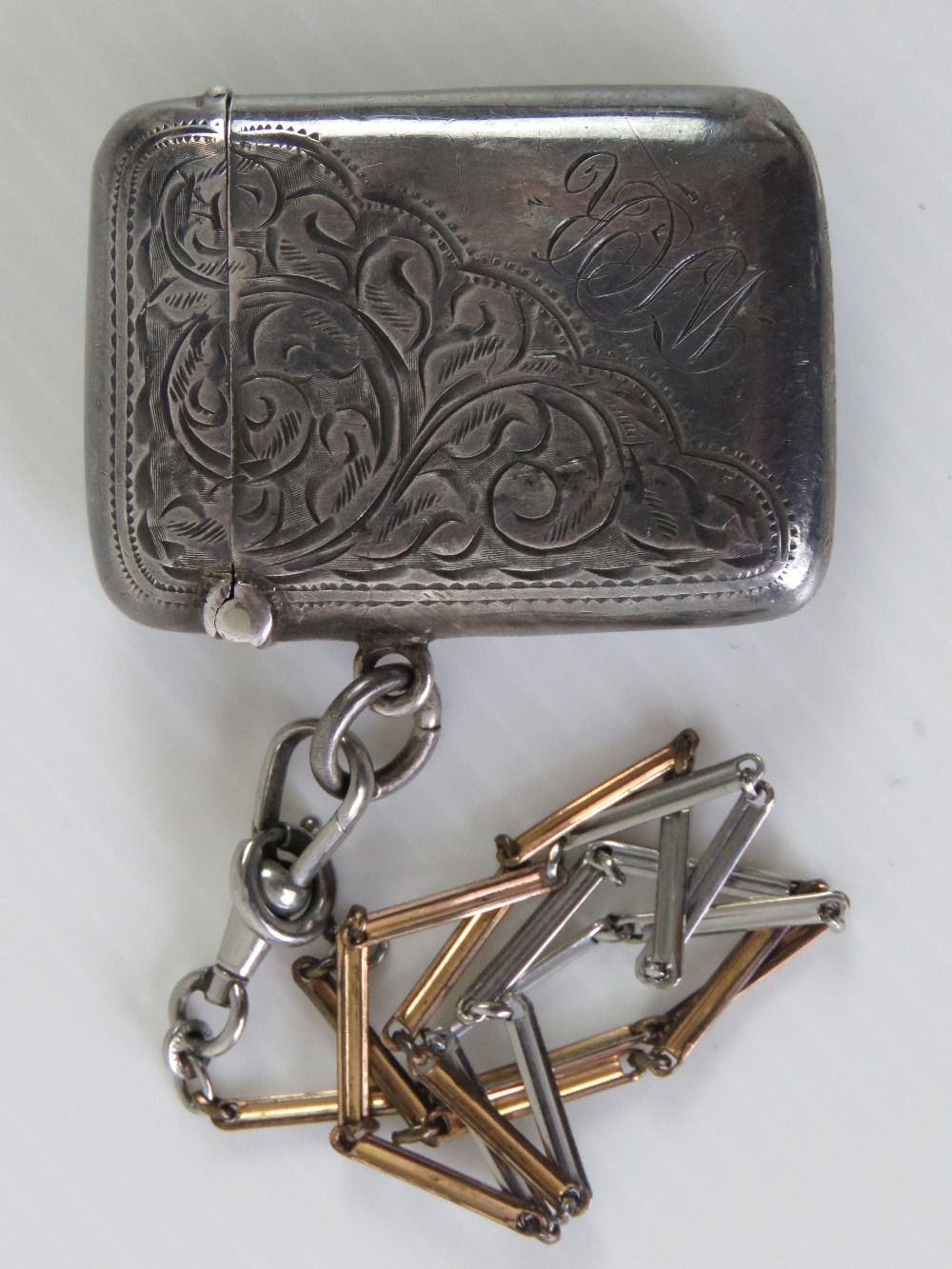 A HM silver vesta case, Birmingham 1906, with attached white and rose metal chain, total weight 0.