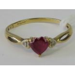 A 9ct gold ring with heart shaped garnet flanked by a pair of illusion set diamonds, hallmarked 375,