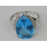 A 9ct white gold ring set with large teardrop cut topaz flanked by row of white stones to each side,