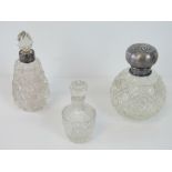 Three cut glass perfume bottles; one with HM silver lid depicting cherubs (London 1904),