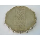 A white metal compact with pie crust edge and engraved floral design,