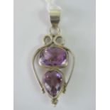 A silver and amethyst pendant, open design set with two large faceted amethysts,