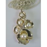 A silver and pearl necklace, five graduated flowers each with a pearl centre, stamped 925, 5cm long,