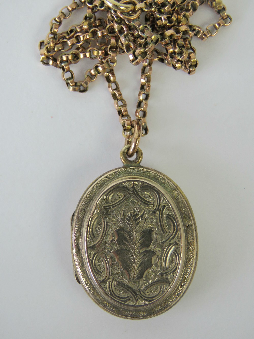 A rose metal Victorian locket with floral engraving, on a 9ct gold belcher link chain, 52cm long,