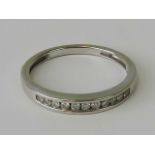 A 9ct white gold and diamond ring, channel set row of eleven round cut diamonds, approx 0.