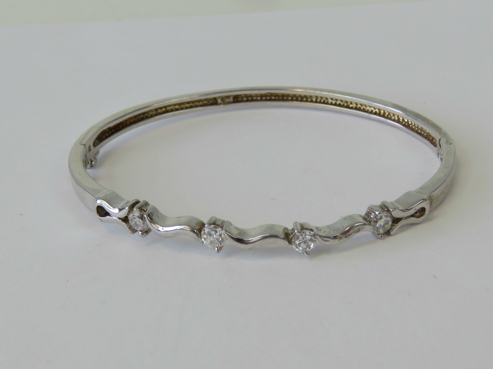 A silver hinged bangle, wave design set with round white stones, stamped 925.