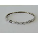 A silver hinged bangle, wave design set with round white stones, stamped 925.