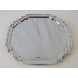 A superb HM silver square-shaped salver, unengraved and raised over four scrolled feet.