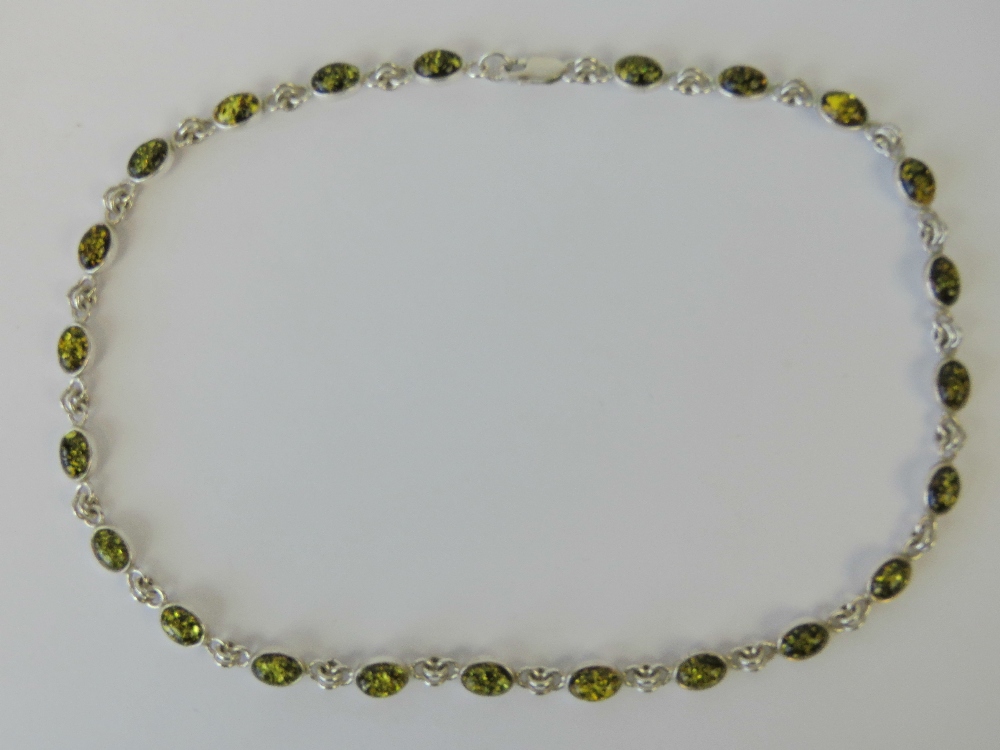 A silver and amber necklace, each oval amber cabachon set in its own panel, stamped 925, 40cm long.