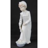 A Nao figurine of a girl in nightdress washing her feet, 29cm high.