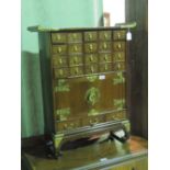 A small 20th century multi-drawer Oriental hardwood cabinet having two doors and brass fittings,