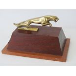 A reproduction brass Jaguar car mascot mounted on a hardwood plinth, 17cm.