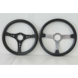 Two leather bound racing car steering wheels being a 'Classic Sport' and a 'Grand Prix',