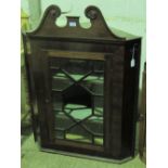 A late Georgian mahogany hanging corner cabinet with glazed door opening to reveal straight cut