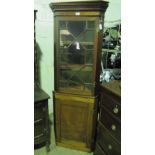 An Edwardian floor standing corner cabinet having glazed upper door and solid lower door,