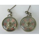A pair of white metal earrings in the form of roulette wheels, complete with ball bearing.