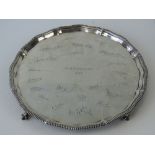 An HM silver hallmarked salver 'HMS Dragon 1933' raised over four ball and claw feet,