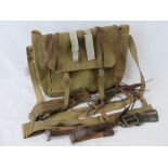 A WWII canvas bag containing a quantity of belts and leather straps within.