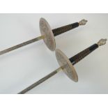 A pair of contemporary fencing foils with engraved hilts and blades.