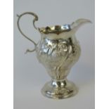 A Georgian HM silver cream jug with floral repoussé body and single foot,