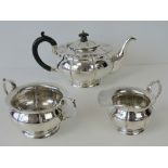 A HM silver three piece tea service; tea pot with ebonised wooden handle and finial,