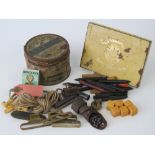 A vintage gold block tin containing a quantity of crayons, rubbers, belt clasps,