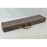 A vintage brown leather gun case, lid lifting to reveal single green baize gun compartment within,