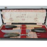 A Buffalo horn handled carving set including knife, fork and sharpener,