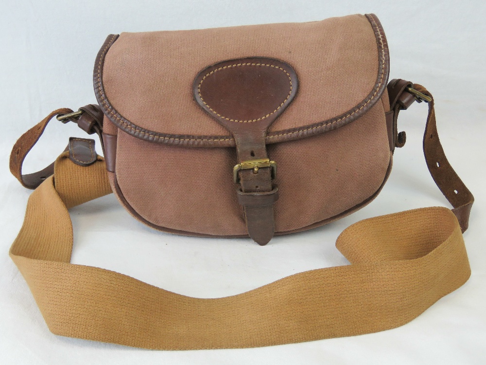 A canvas cartridge bag with leather and canvas strap, approx 25cm wide.