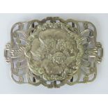 A large white metal belt buckle, central circular plaque with repoussé depiction of cherubs,