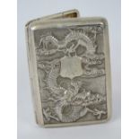 A Chinese white metal cigarette case featuring a repoussé four-toed dragon encircling an engraved