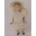 A miniature porcelain doll with bisque head, having painted features and stamped '130 over 2',