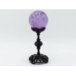 AN ORIENTAL CARVED AND PIERCED HARDWOOD STAND SUPPORTING A POLISHED QUARTZ CRYSTAL BALL 15 CM HIGH