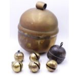 A LARGE BRASS BALL FORM BELL OR RATTLE APPROX 33CM AND SIX SMALLER SIMILAR BELLS.
