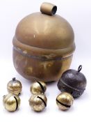 A LARGE BRASS BALL FORM BELL OR RATTLE APPROX 33CM AND SIX SMALLER SIMILAR BELLS.