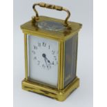 A BRASS CASED CARRIAGE CLOCK, TYPICAL FIVE GLASS FORM WITH VISIBLE ESCAPEMENT, WHITE ENAMEL DIAL