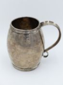 A SILVER METAL BARREL FORM DRINKING TANKARD WITH SCROLL FORM HANDLE. ENGRAVED TO BASE "Bidal" AND
